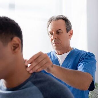 A doctor performs a diagnostic examination of a patient with neck pain.